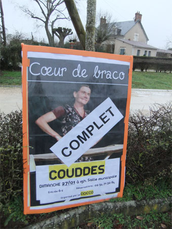 En extérieur, grande pancarte du spectacle à Couddes Loir-et-Cher
                      avec un bandeau en travers qui indique complet.