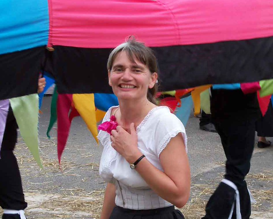 Véronique Blot comédienne auteure chanteuse
Crédit photo Union pour la Culture Populaire en Sologne UCPS Véronique Blot sourit. Elle porte une habit traditionnel de Sologne et a
une fleur rouge en papier à la main. La scène se passe pendant la fête Berdigne
Berdogne à Couddes Loir-et-Cher