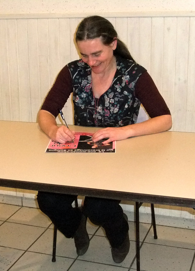 Après le spectacle, dans la salle des fêtes de Neuvy-en-Sullias
                        Loiret, Véronique Blot, en costume de Bernadette, est assise à une
                        table et signe une affiche,