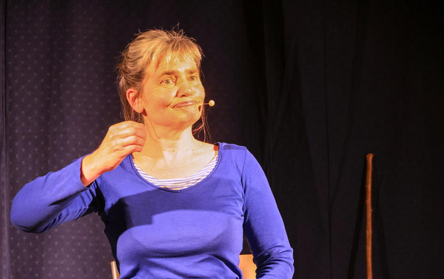 Véronique Blot sur scène incarnant Rosalie avec vue sur le décor : une
    	chaise et un bâton